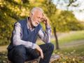 Älterer Mann sitzt in der Natur und denkt nach
